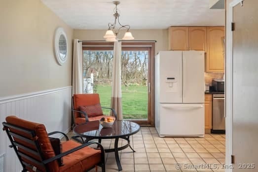 127 Pleasant View Rd, Derby, CT 06418 - interior space featuring stainless steel dishwasher, wainscoting, light brown cabinets, white fridge with ice dispenser, and light tile patterned floors