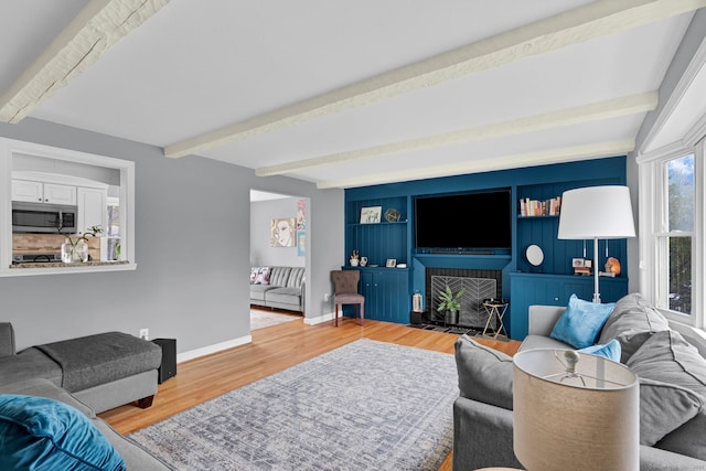 living area featuring wood finished floors, beamed ceiling, and baseboards