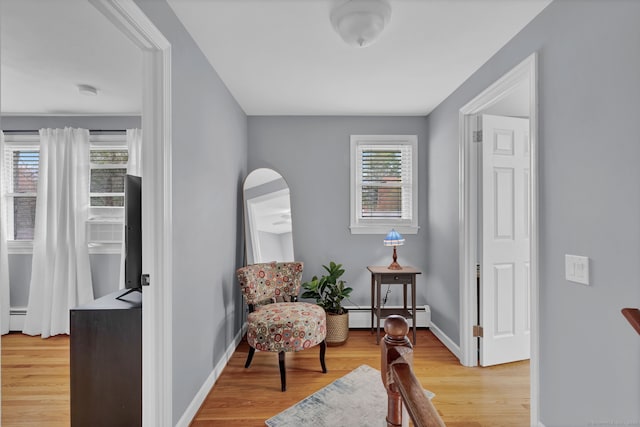 living area with light wood finished floors, arched walkways, baseboard heating, and baseboards