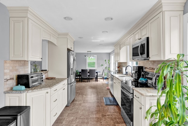 kitchen with tasteful backsplash, light stone countertops, appliances with stainless steel finishes, and a sink