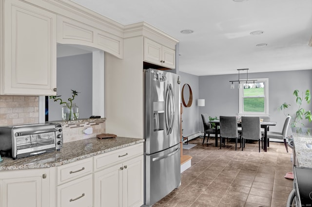 kitchen featuring light stone counters, decorative backsplash, a toaster, decorative light fixtures, and stainless steel fridge with ice dispenser