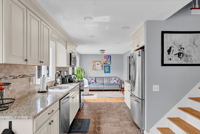kitchen featuring light stone counters, appliances with stainless steel finishes, decorative backsplash, and a sink