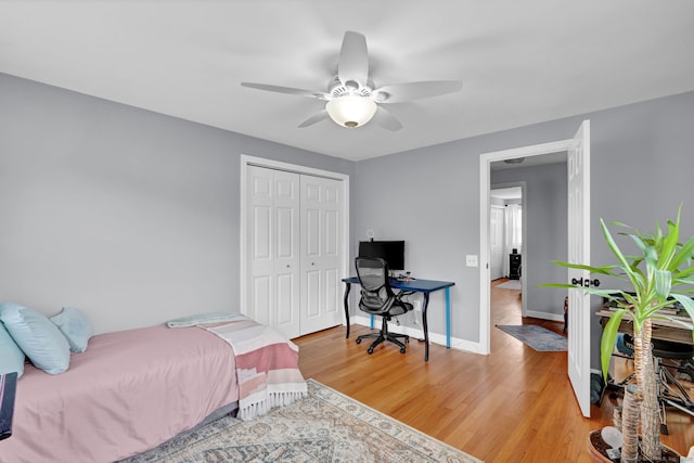 bedroom featuring light wood-style floors, ceiling fan, baseboards, and a closet