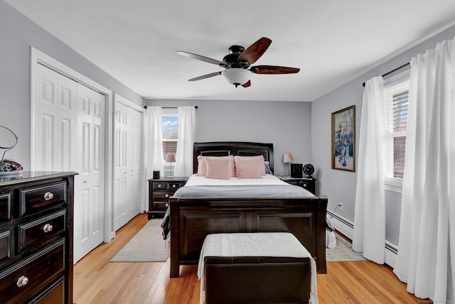bedroom with ceiling fan, light wood-style floors, two closets, and a baseboard radiator