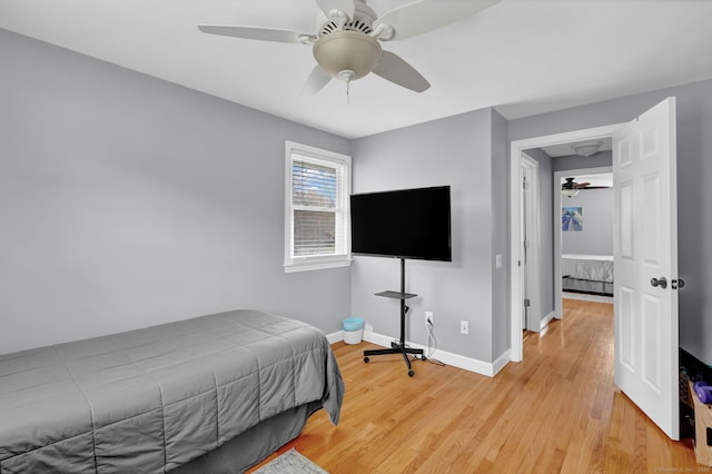 bedroom with light wood-type flooring, a ceiling fan, and baseboards