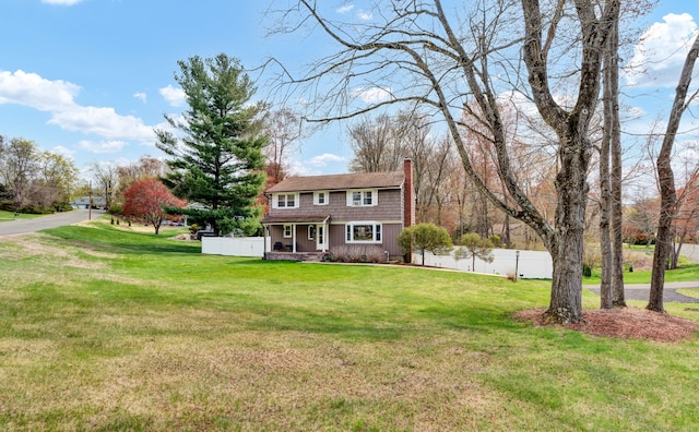 view of front of house with fence, a front yard, a chimney, and a porch