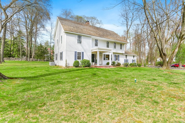 colonial house with a front lawn, a porch, and a chimney