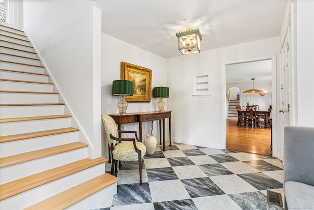 corridor with stairway, baseboards, and a chandelier