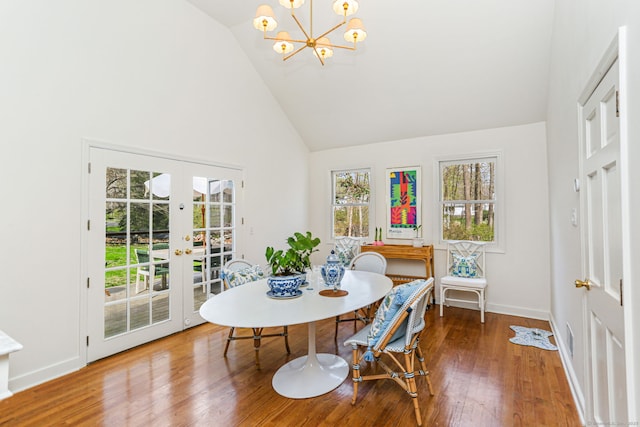 dining space featuring high vaulted ceiling, wood finished floors, a chandelier, french doors, and baseboards