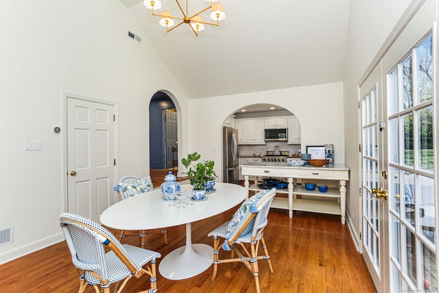 dining room featuring high vaulted ceiling, arched walkways, an inviting chandelier, baseboards, and visible vents