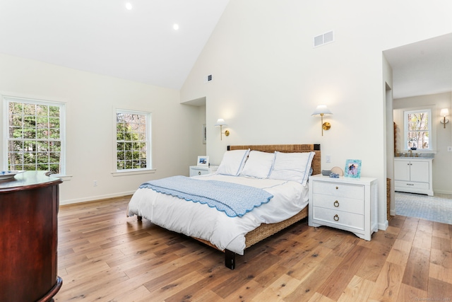 bedroom featuring light wood-style flooring, visible vents, high vaulted ceiling, and multiple windows