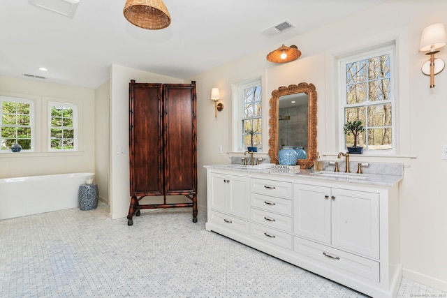 bathroom with double vanity, visible vents, a soaking tub, and a sink