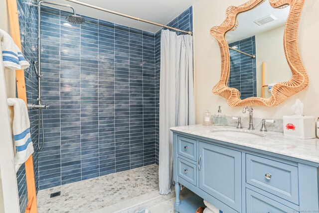 bathroom featuring a tile shower, visible vents, and vanity