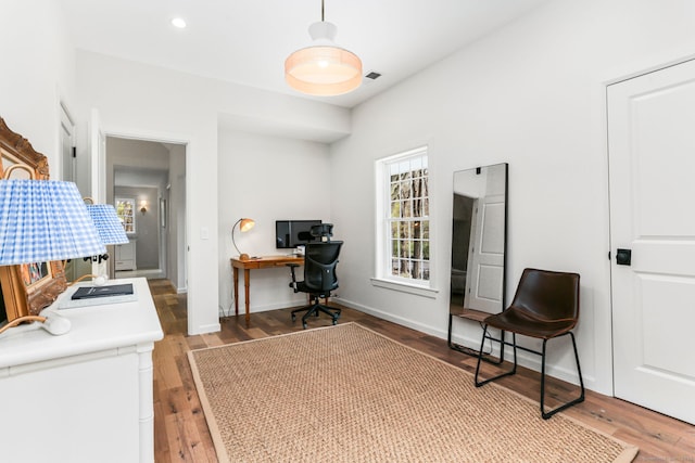 home office with wood finished floors, visible vents, and baseboards