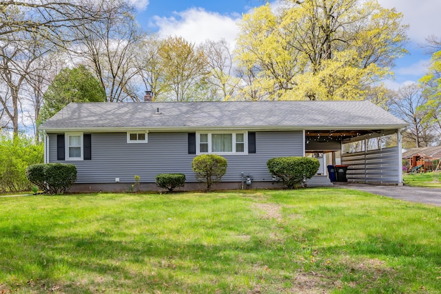 view of front of home featuring a shingled roof, aphalt driveway, an attached carport, a front yard, and a chimney