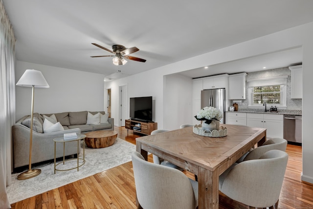 dining space with ceiling fan and light wood-type flooring