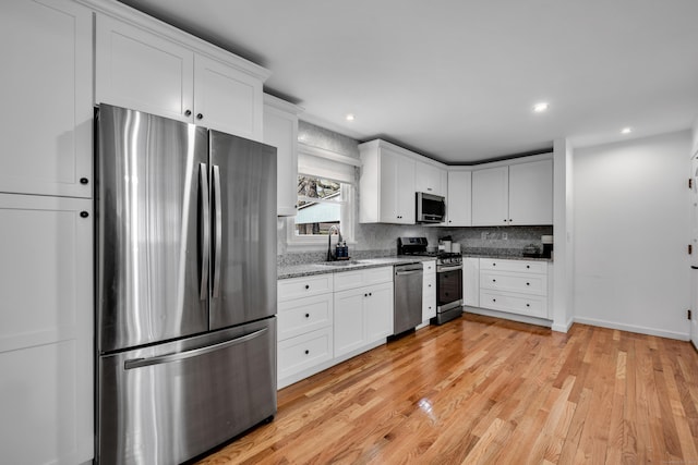 kitchen featuring white cabinetry, appliances with stainless steel finishes, a sink, and light wood-style floors