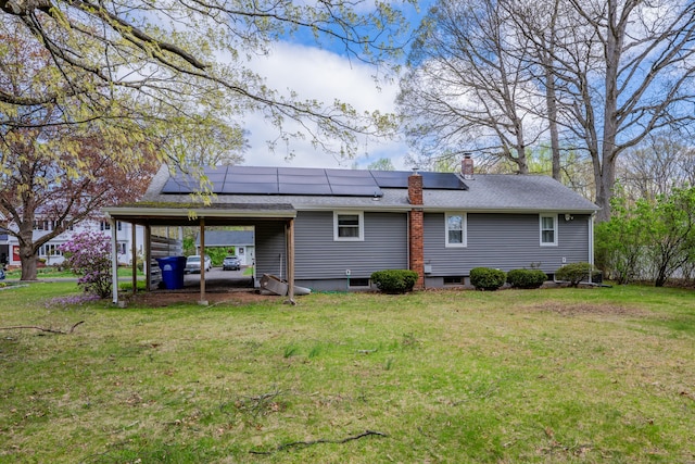 rear view of house featuring a lawn, a chimney, and solar panels