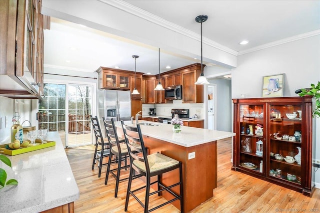 19 Fairchild Rd, Newtown, CT 06470 - kitchen featuring brown cabinets, a breakfast bar, appliances with stainless steel finishes, light wood-style flooring, and ornamental molding