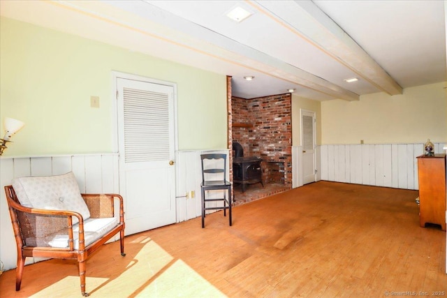 19 Fairchild Rd, Newtown, CT 06470 - living area featuring a wood stove, beam ceiling, a wainscoted wall, and wood finished floors
