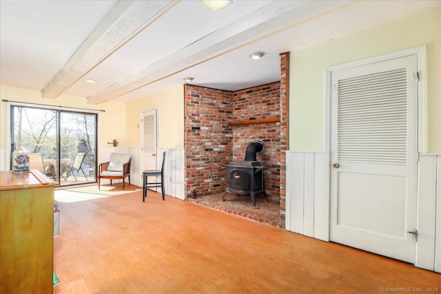 19 Fairchild Rd, Newtown, CT 06470 - living area featuring wood finished floors, a wood stove, beam ceiling, and a wainscoted wall
