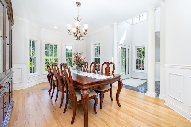 176 Fox Hollow Ln, Bristol, CT 06010 - dining space with light wood-style flooring, a chandelier, crown molding, a wainscoted wall, and a decorative wall