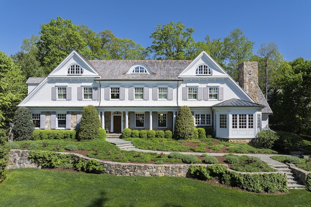 view of front of home featuring a chimney, a porch, and a front yard