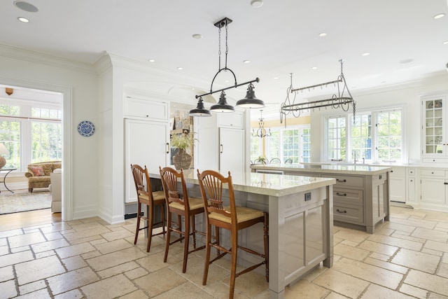 kitchen with a spacious island, stone tile floors, crown molding, recessed lighting, and healthy amount of natural light