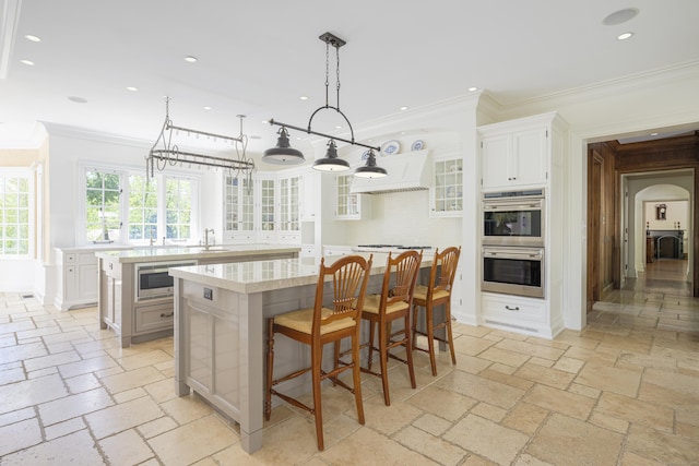 kitchen featuring a center island, appliances with stainless steel finishes, a sink, ornamental molding, and light countertops