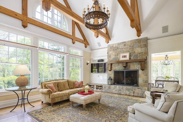 living area featuring high vaulted ceiling, a chandelier, beam ceiling, wood finished floors, and a stone fireplace