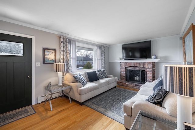living area with a fireplace, wood finished floors, crown molding, and baseboard heating