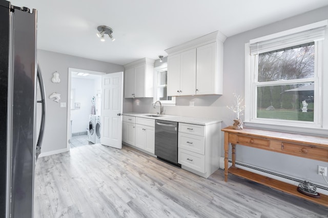 kitchen with independent washer and dryer, white cabinetry, light wood-style flooring, stainless steel appliances, and light countertops