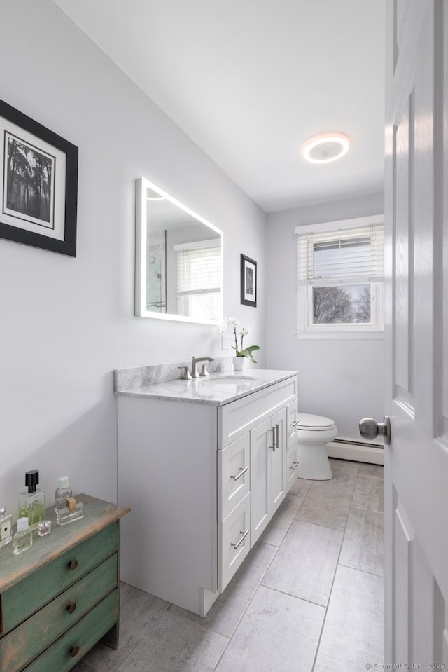 bathroom with baseboard heating, a wealth of natural light, toilet, and vanity