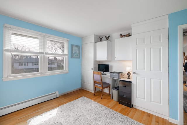 home office with baseboard heating, baseboards, and light wood finished floors