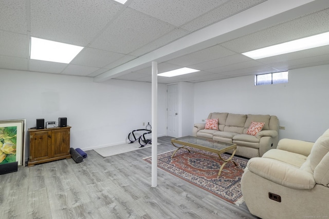 living room with wood finished floors, a drop ceiling, and baseboards