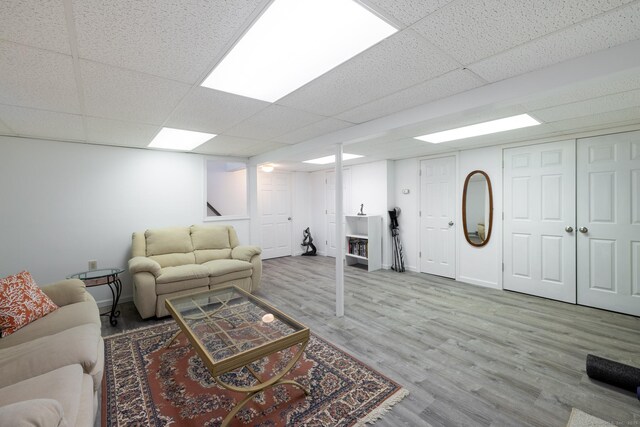 living area with wood finished floors, a paneled ceiling, and stairs