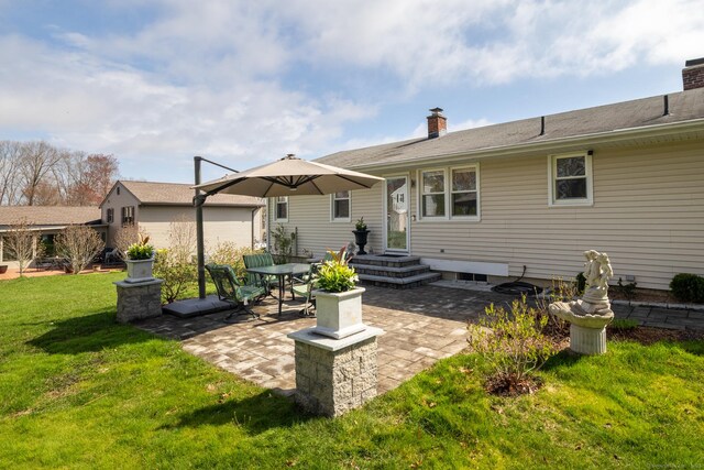 back of property with a patio area, a lawn, and a chimney