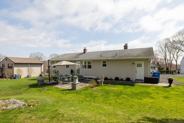 back of house with a lawn, a chimney, and a patio