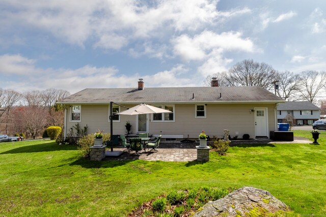 back of house with a patio, a yard, and a chimney