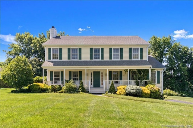 colonial inspired home featuring a porch, a chimney, and a front lawn