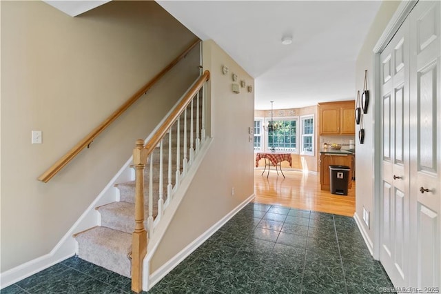 stairs with baseboards and a notable chandelier