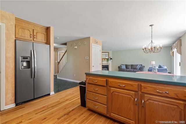 kitchen with dark countertops, a notable chandelier, light wood finished floors, stainless steel fridge with ice dispenser, and open floor plan