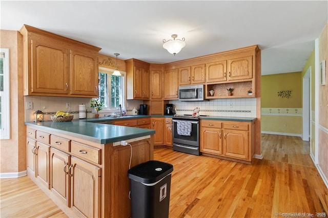 kitchen featuring appliances with stainless steel finishes, light wood-type flooring, a sink, baseboards, and a peninsula