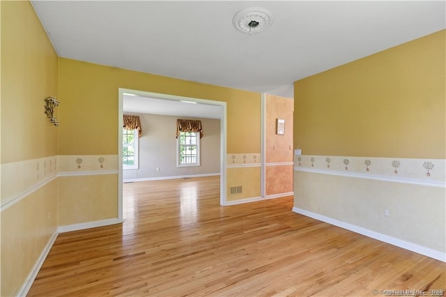 spare room with baseboards, visible vents, and light wood-type flooring