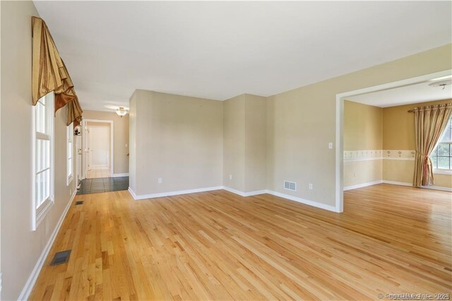 unfurnished room featuring visible vents, light wood-style floors, and baseboards