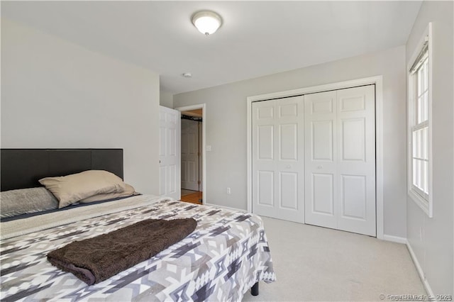 bedroom with baseboards, a closet, and light colored carpet