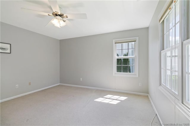 unfurnished room with light colored carpet, a ceiling fan, and baseboards