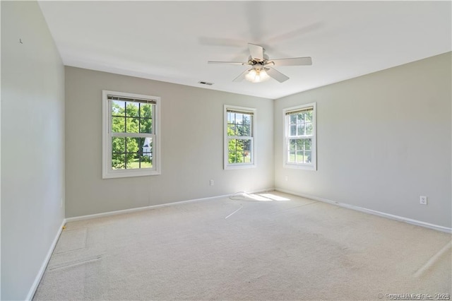 carpeted spare room with ceiling fan, visible vents, and baseboards