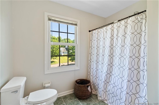 bathroom featuring toilet, baseboards, and a shower with curtain
