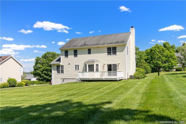 rear view of property featuring a lawn, a wooden deck, and a chimney